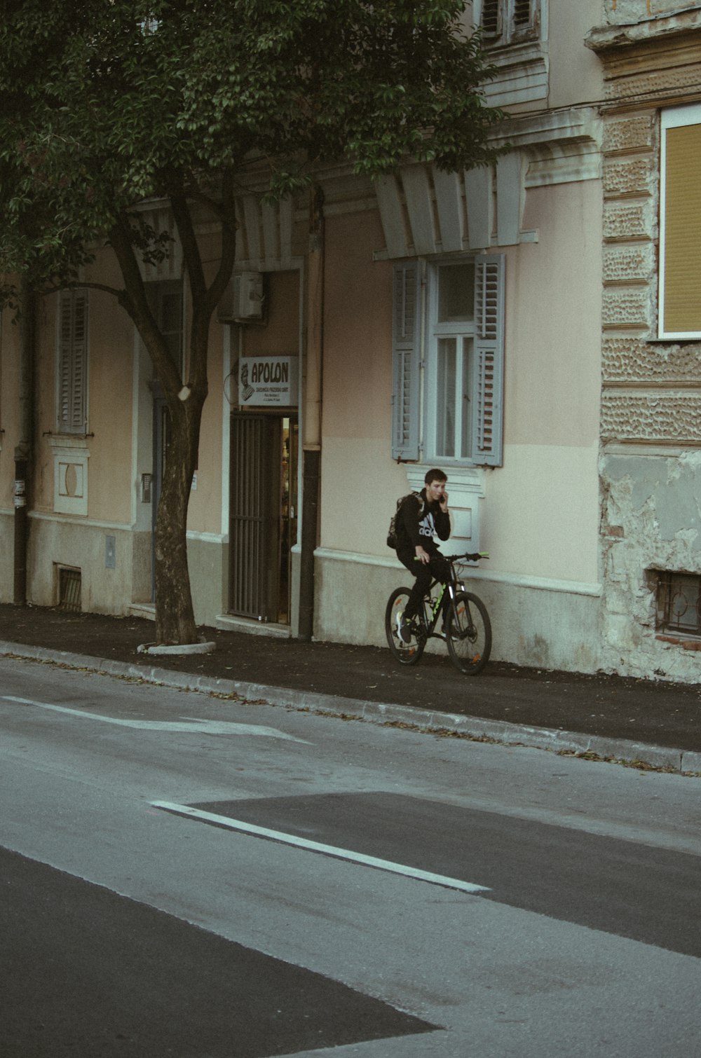 a man riding a bike down a street next to a tall building