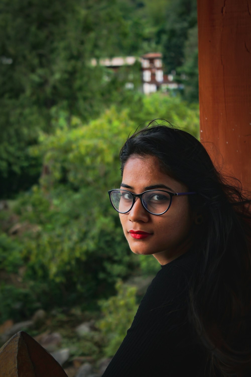 a woman wearing glasses sitting on a wooden bench