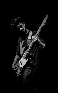 Portrait of the first band member playing guitar with a focused expression.