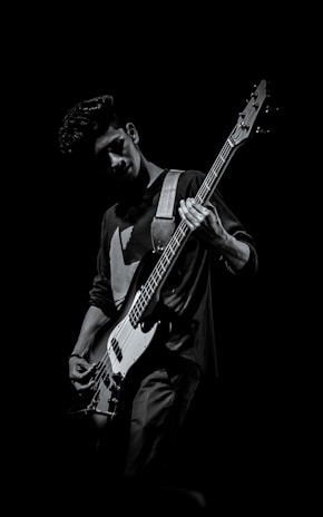 Portrait of the first band member playing guitar with a focused expression.