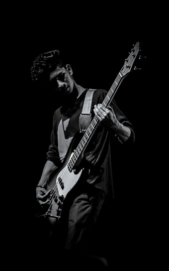 A close-up shot of Tony Gregory playing guitar with intense focus in a dimly lit studio.