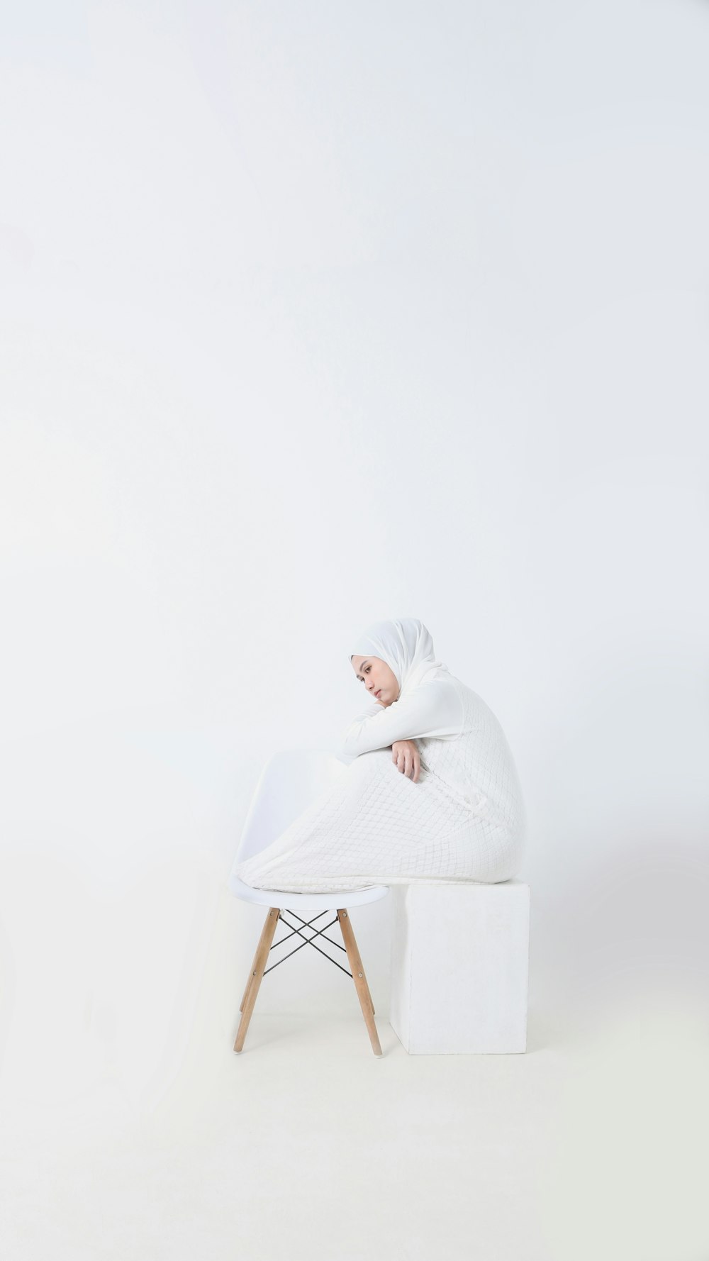 a woman in a white robe sitting on a white bench