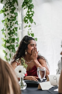 a woman covers her face as she sits at a table