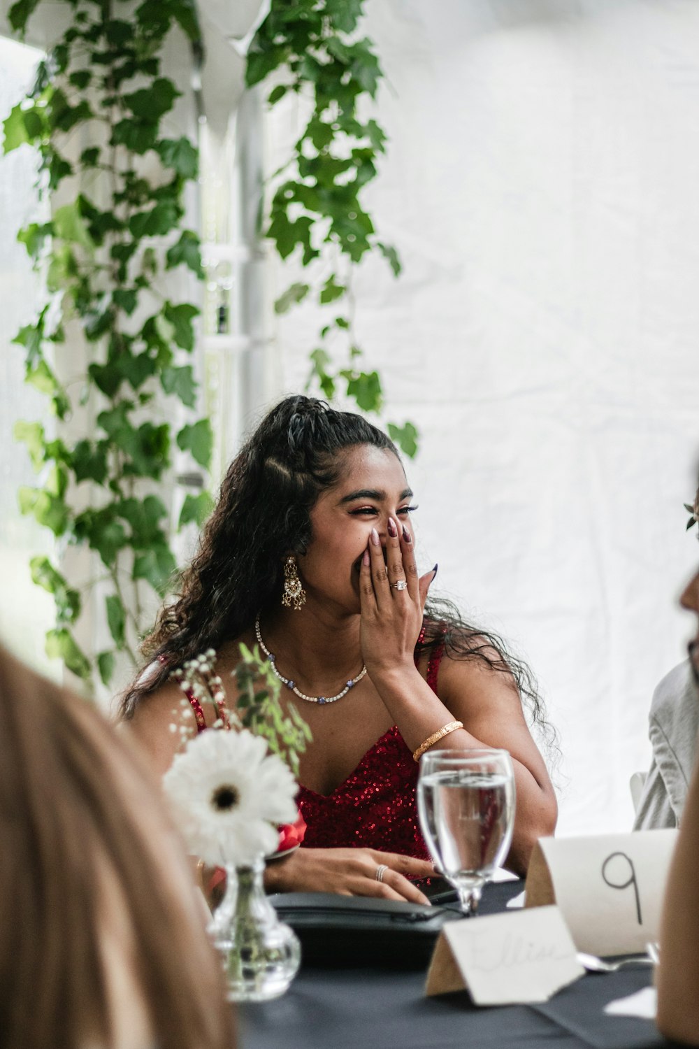 a woman covers her face as she sits at a table