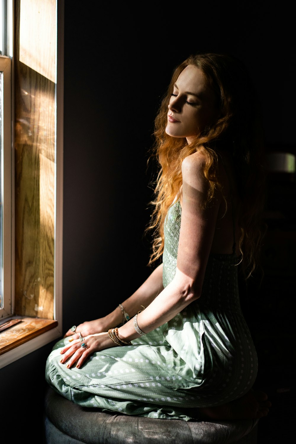 a woman sitting on a stool looking out a window