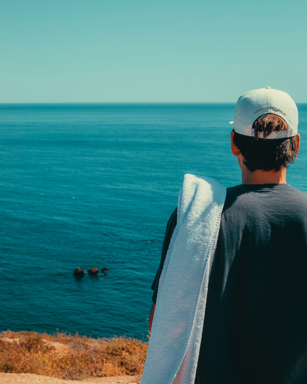 a man standing on top of a cliff next to the ocean