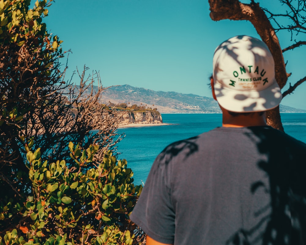 a man wearing a hat looking out over the ocean