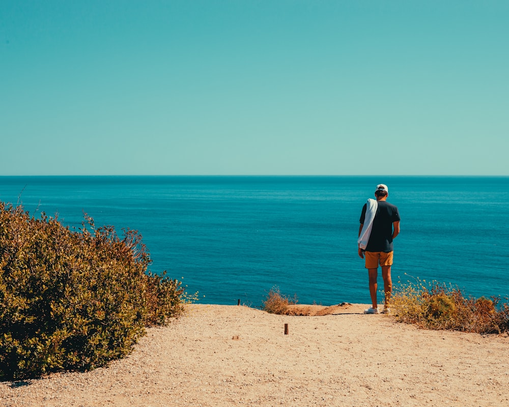 a man standing on top of a sandy beach next to the ocean