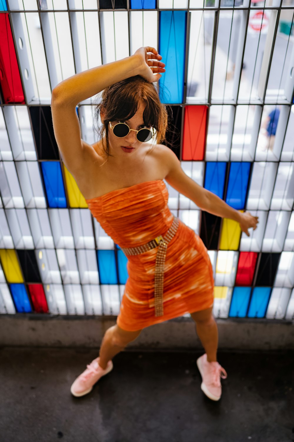 a woman in an orange dress dancing in front of a colorful wall