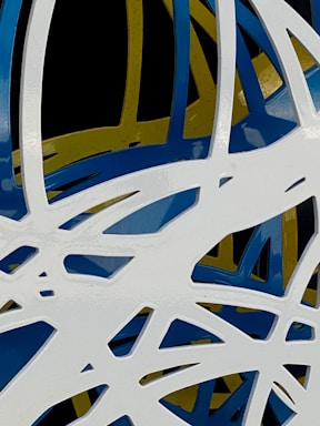 An abstract composition featuring intertwined and overlapping organic shapes in white, blue, and yellow against a black background. The shapes are sleek and glossy, creating a dynamic and modern aesthetic.