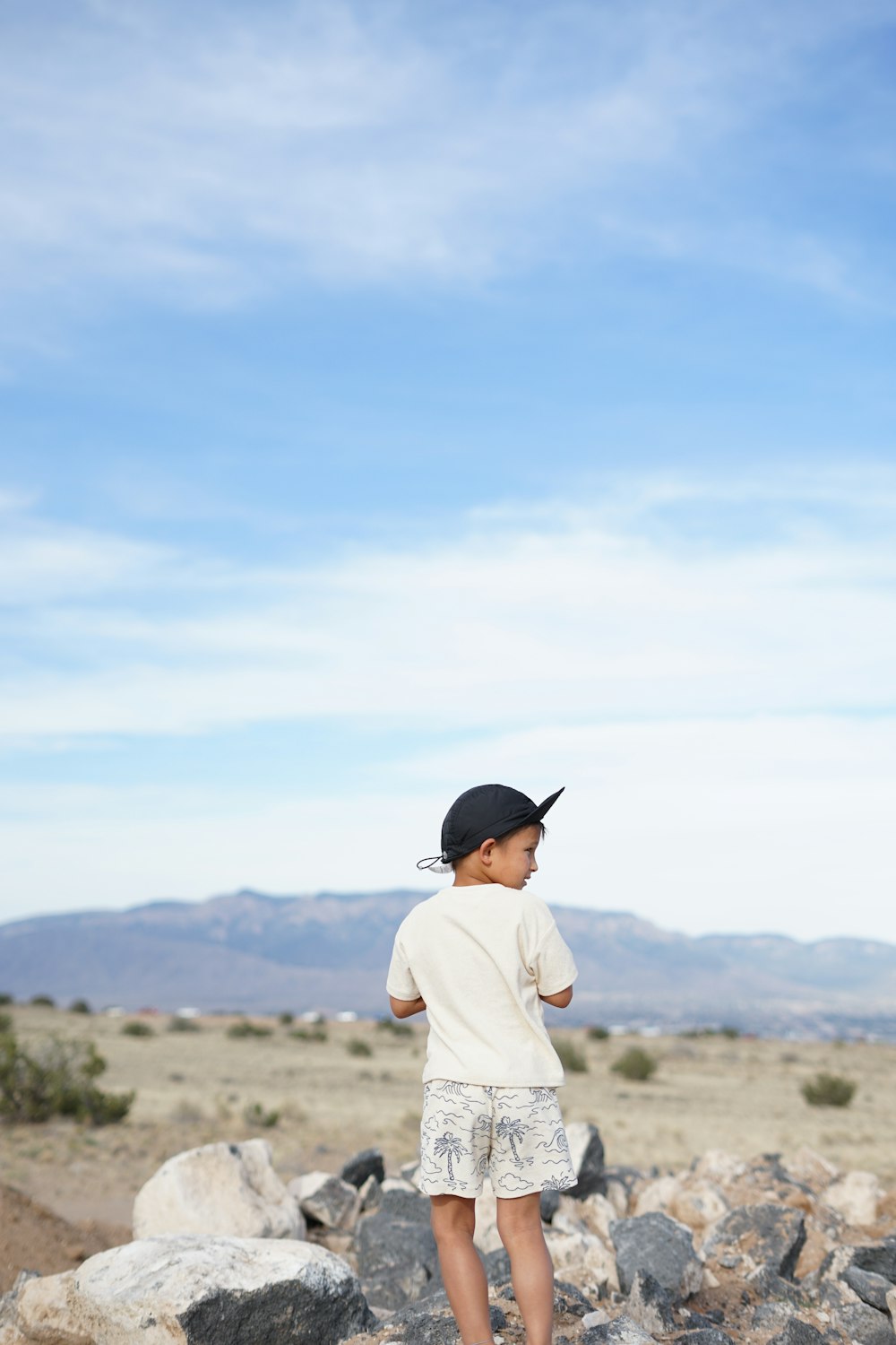 a young boy standing on top of a pile of rocks