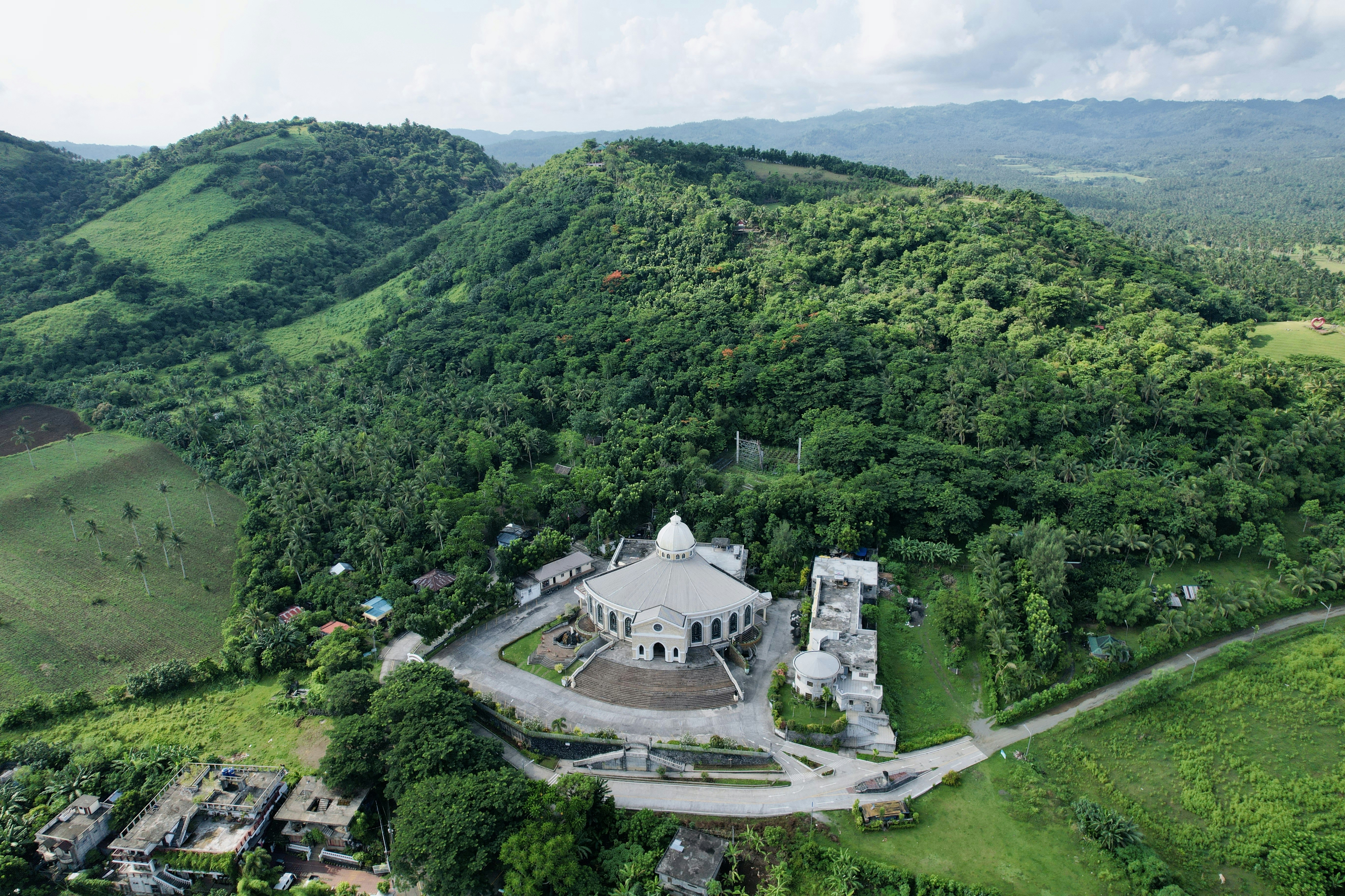 an aerial view of a large white building in the middle of a lush green valley