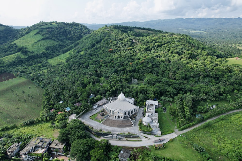 an aerial view of a large white building in the middle of a lush green valley