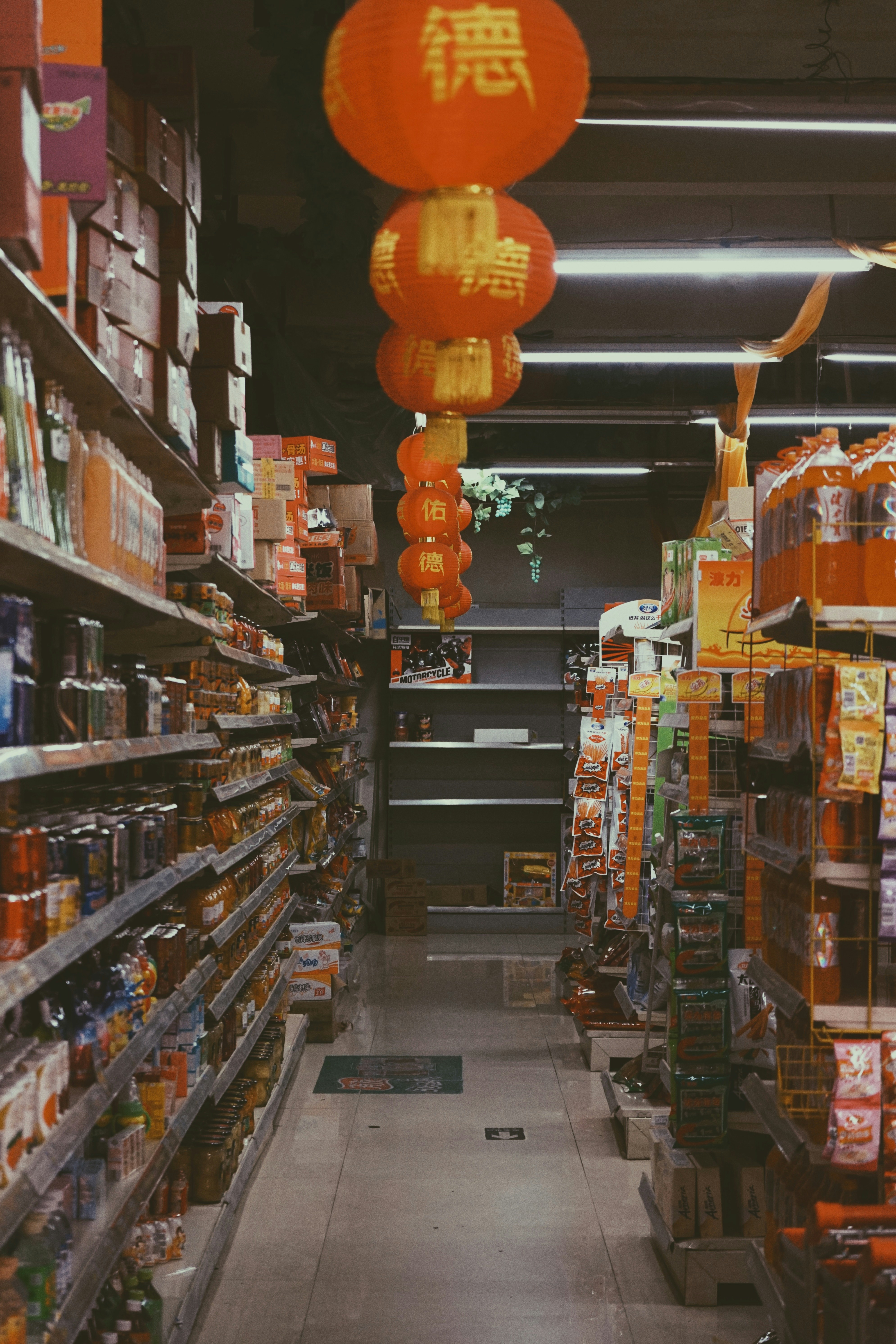 a grocery store aisle with orange lanterns hanging from the ceiling