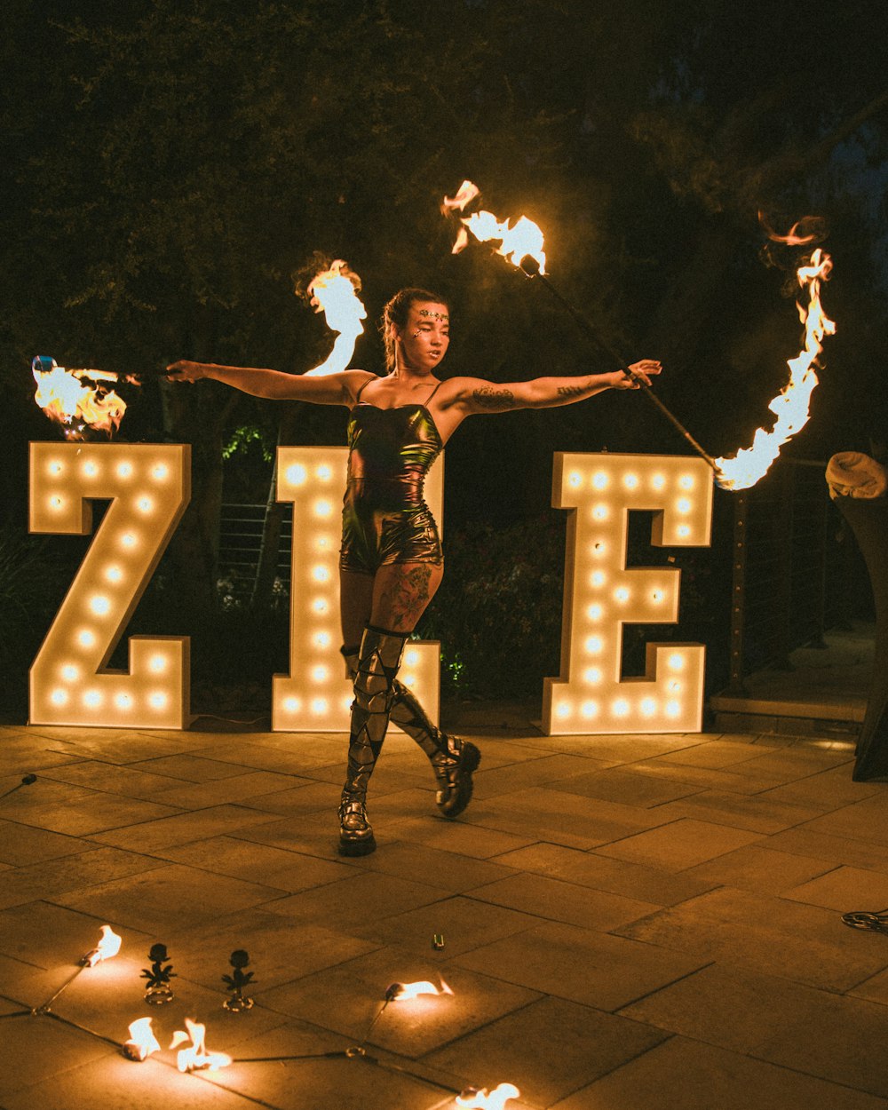 a woman is dancing in front of a sign with fire