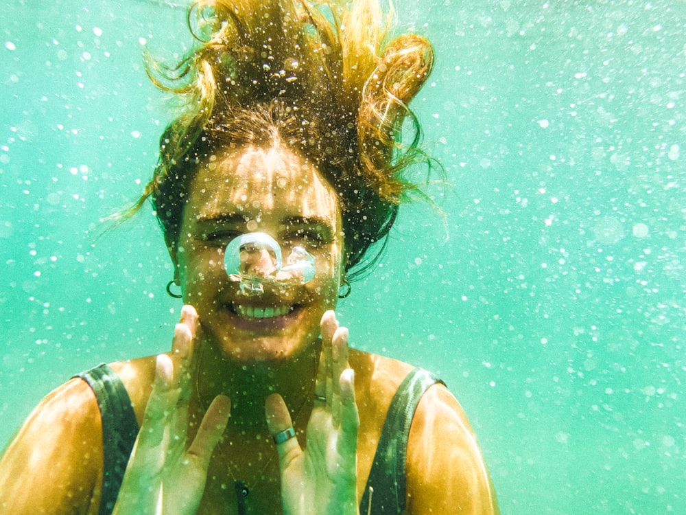 uma mulher debaixo d'água com uma bolha na boca