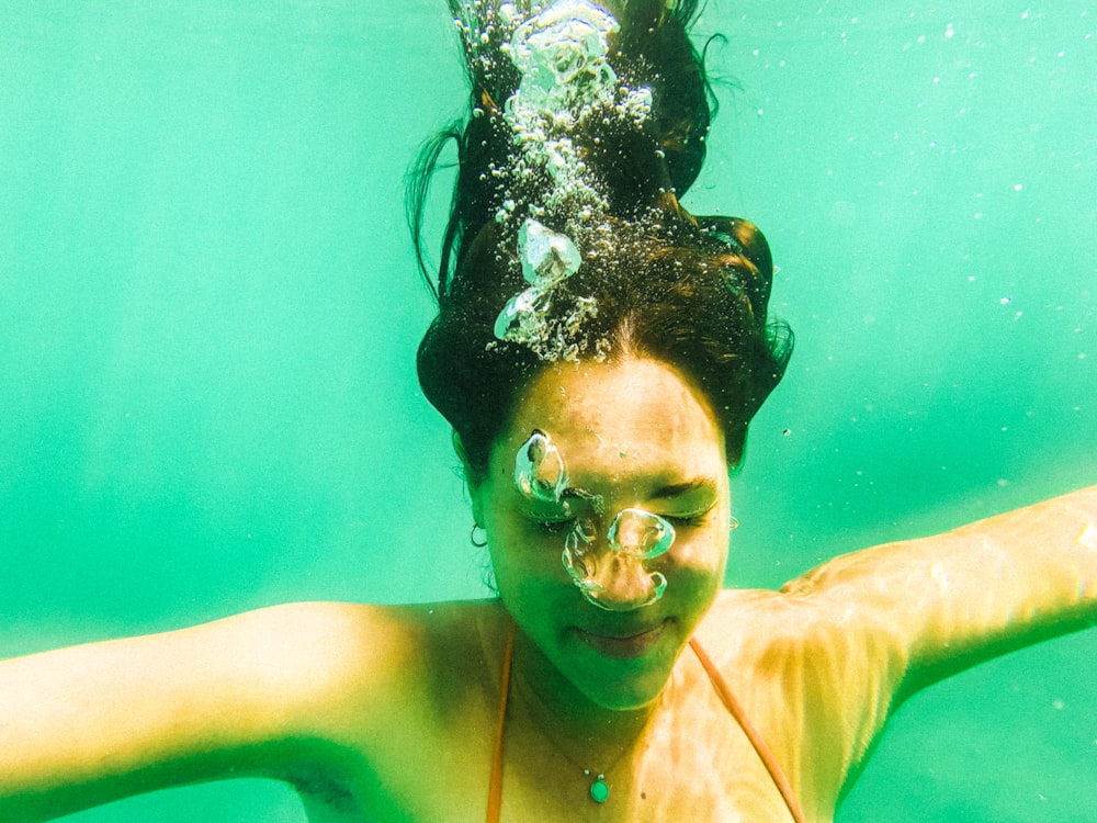 a woman in a bikini swims under water