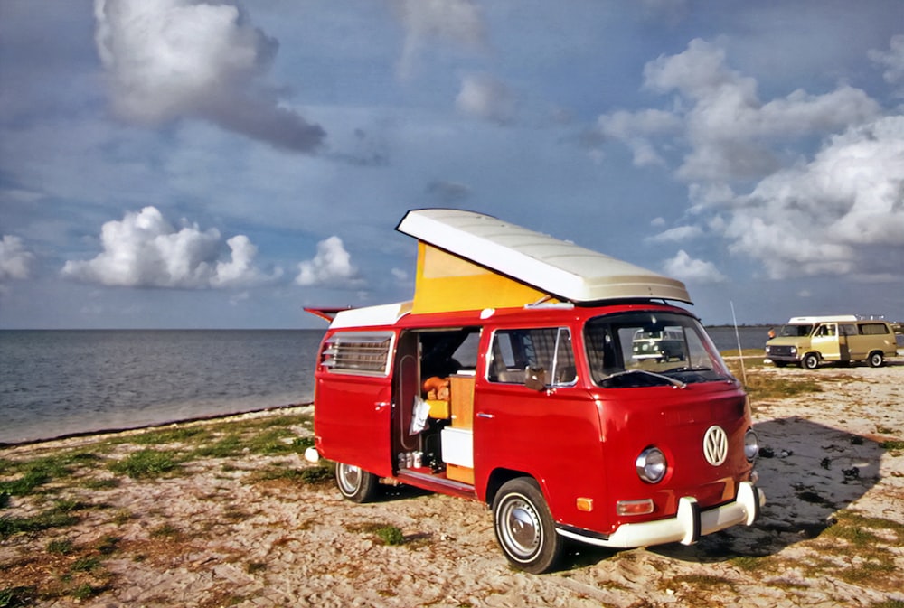 a van parked on the beach with a surfboard on top of it