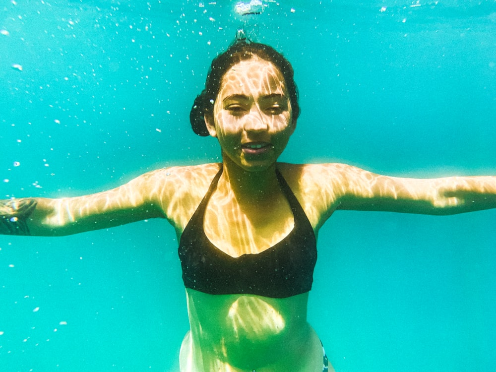 a woman in a bikini swims under water