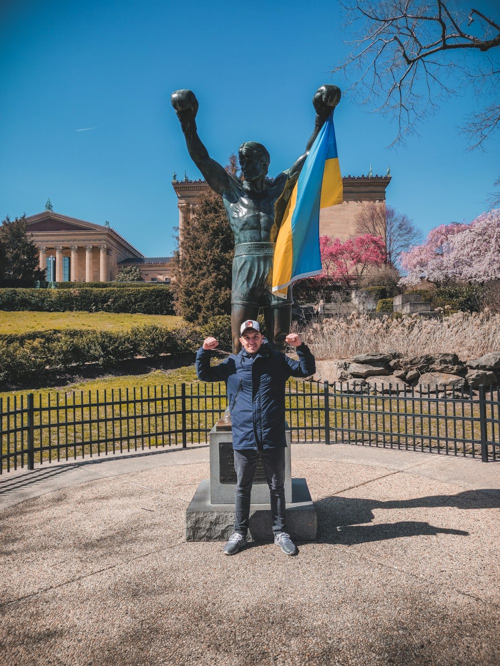 Un hombre parado frente a una estatua de un hombre sosteniendo una bandera