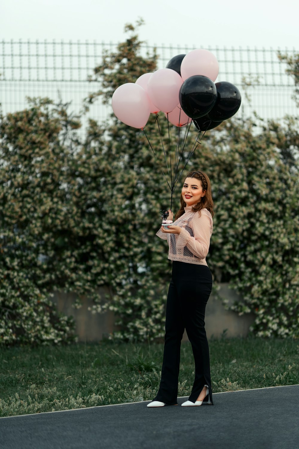 a woman holding a bunch of black and pink balloons