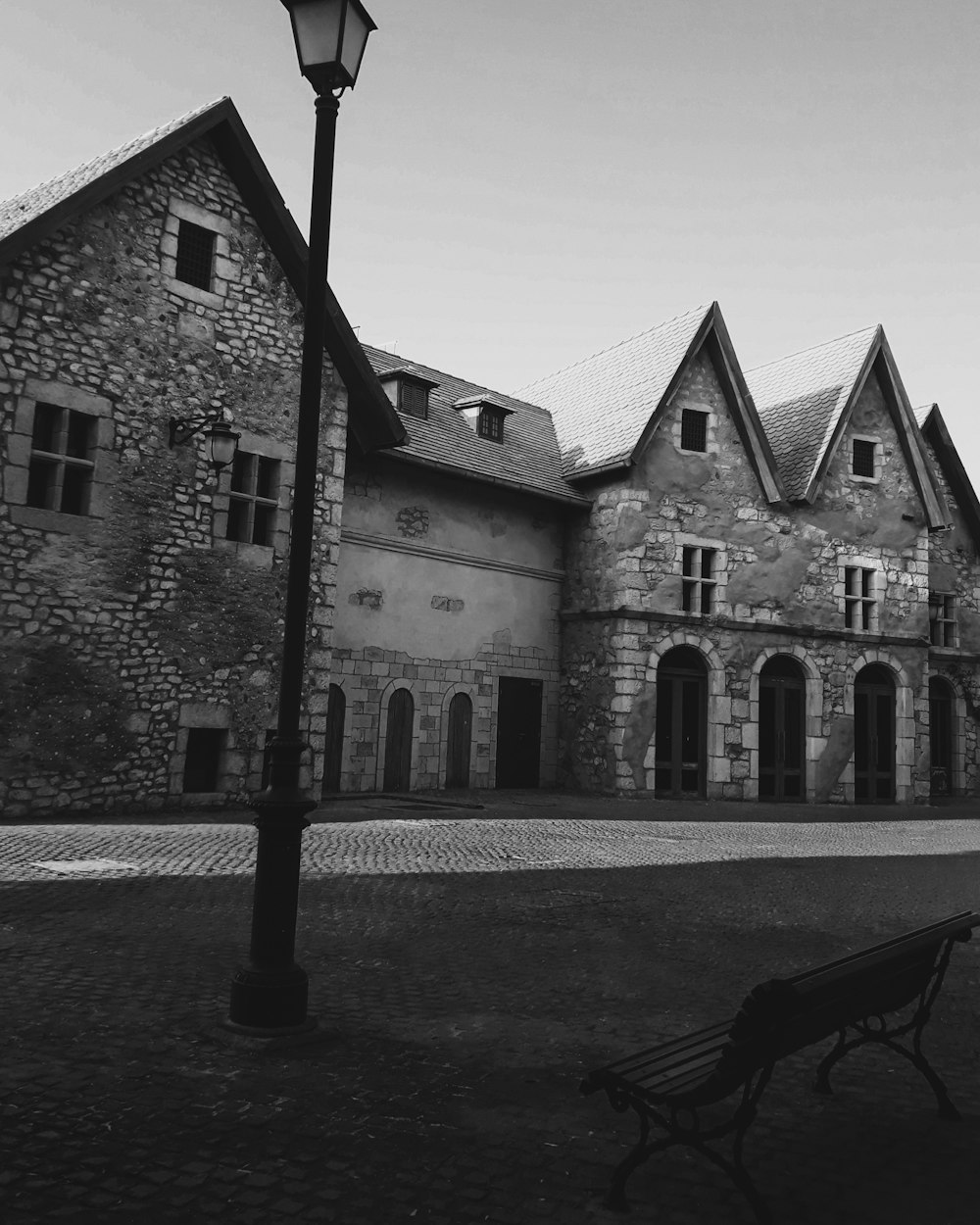 a black and white photo of a bench in front of a building