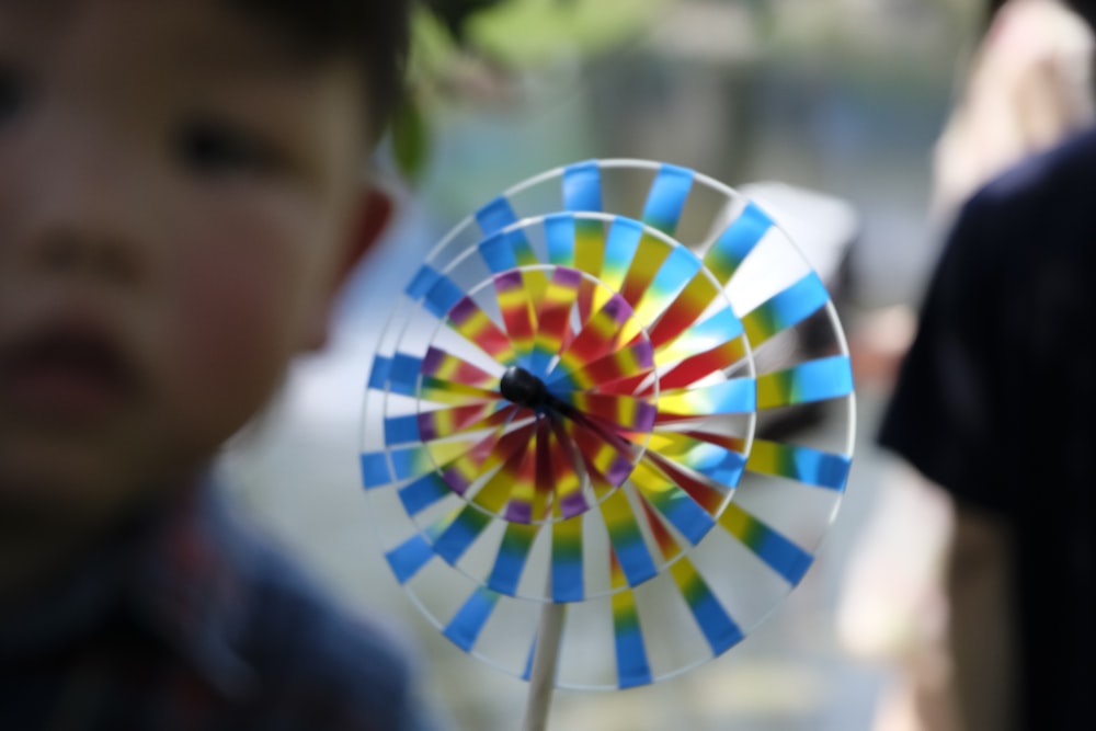 a young boy holding a colorful pinwheel on a stick