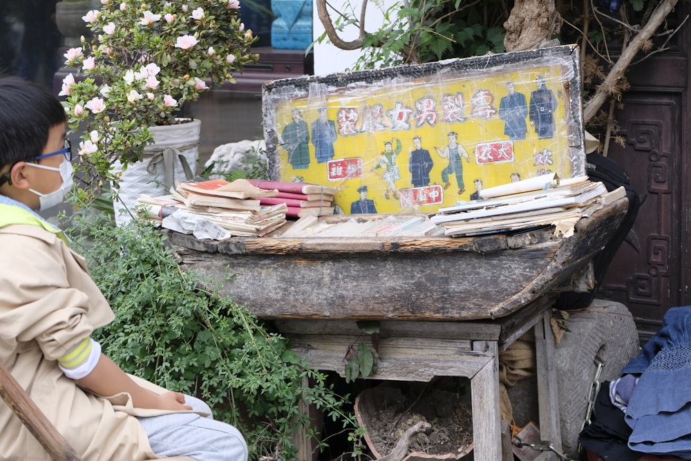 a man sitting in a chair next to a table with a sign on it