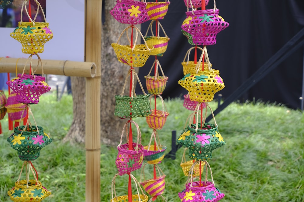 a group of colorful baskets hanging from a wooden pole