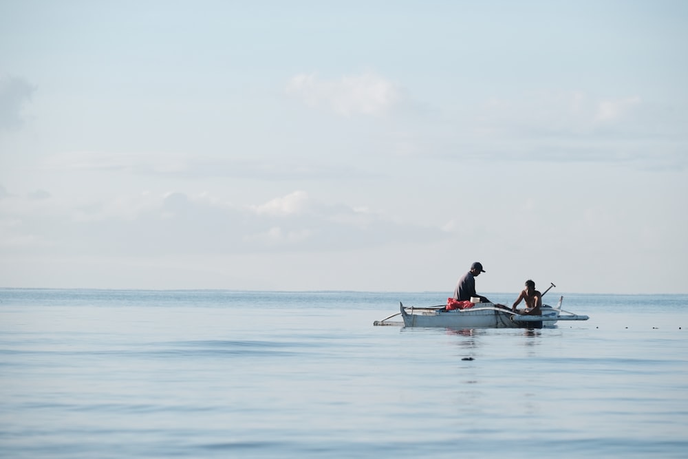 two people in a small boat in the middle of the ocean