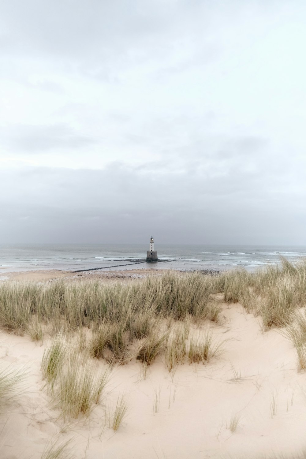 a sandy beach with a light house in the distance
