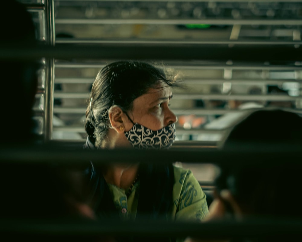 a woman sitting in a bus wearing a face mask