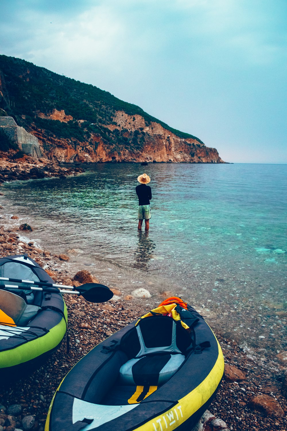 a man standing in the water next to two kayaks