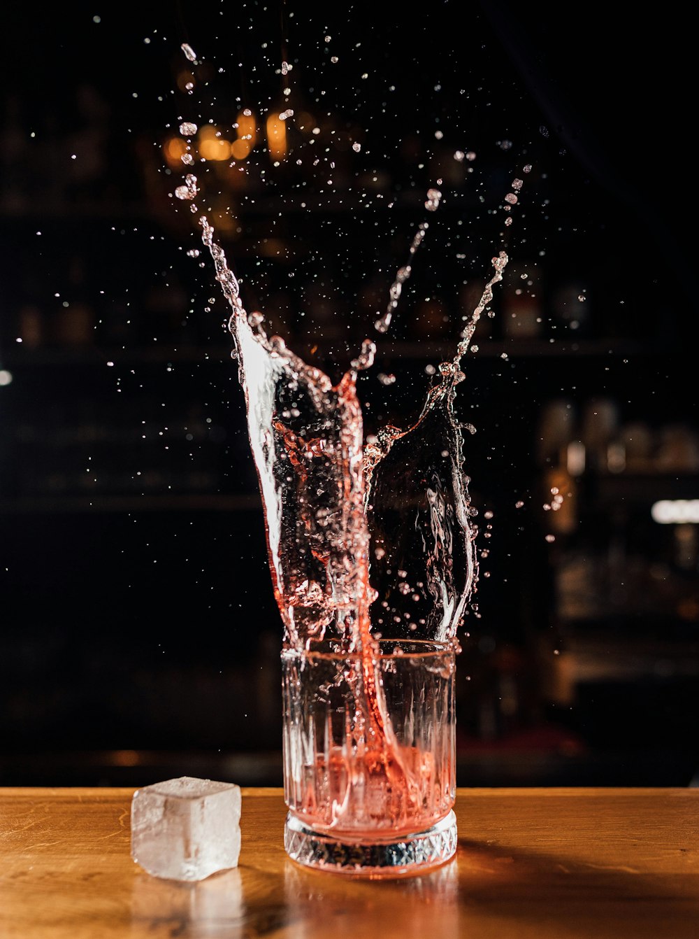 a glass of water with ice cubes on a table