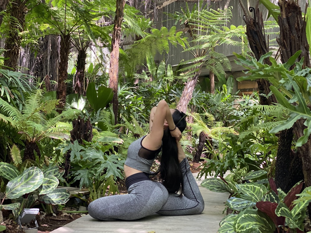a woman is doing yoga in a tropical setting