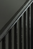 A close-up view of a metal staircase railing with several vertical bars, featuring a dark, muted color scheme.