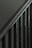 A close-up view of a metal staircase railing with several vertical bars, featuring a dark, muted color scheme.