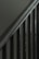 A close-up view of a metal staircase railing with several vertical bars, featuring a dark, muted color scheme.