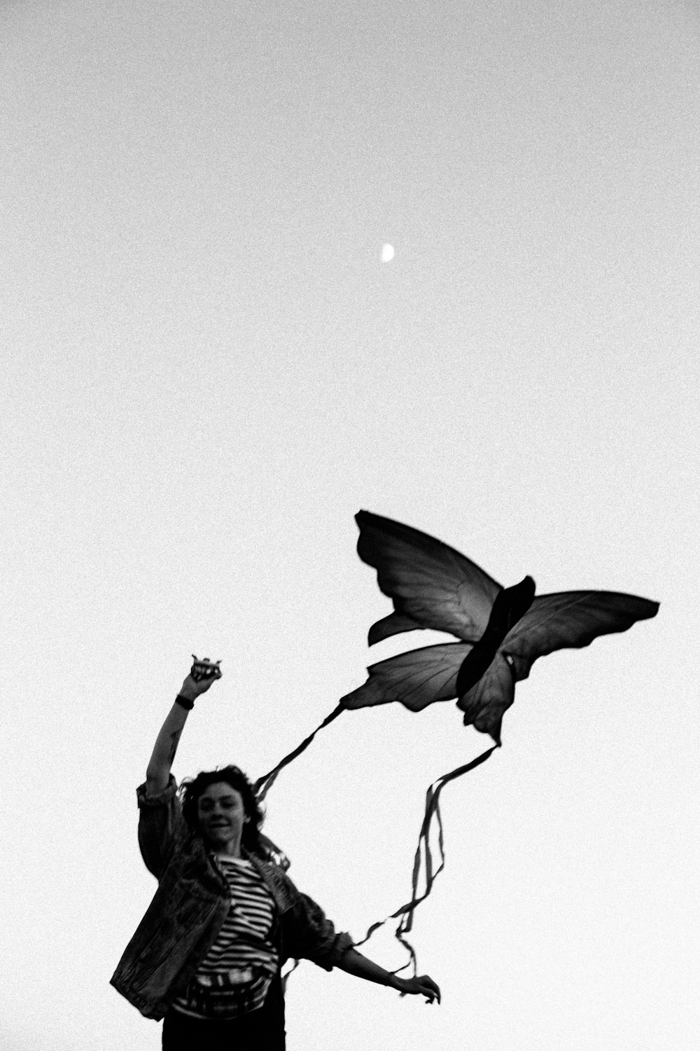 a woman flying a butterfly kite in the sky