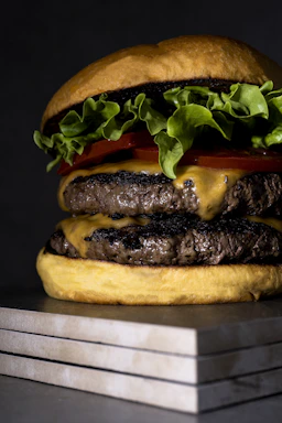Close-up of a juicy Rokko burger with melted cheddar and fresh lettuce on a black slate background