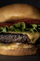 Close-up of a juicy cheeseburger with melted cheddar, fresh lettuce, and tomato on a toasted bun.
