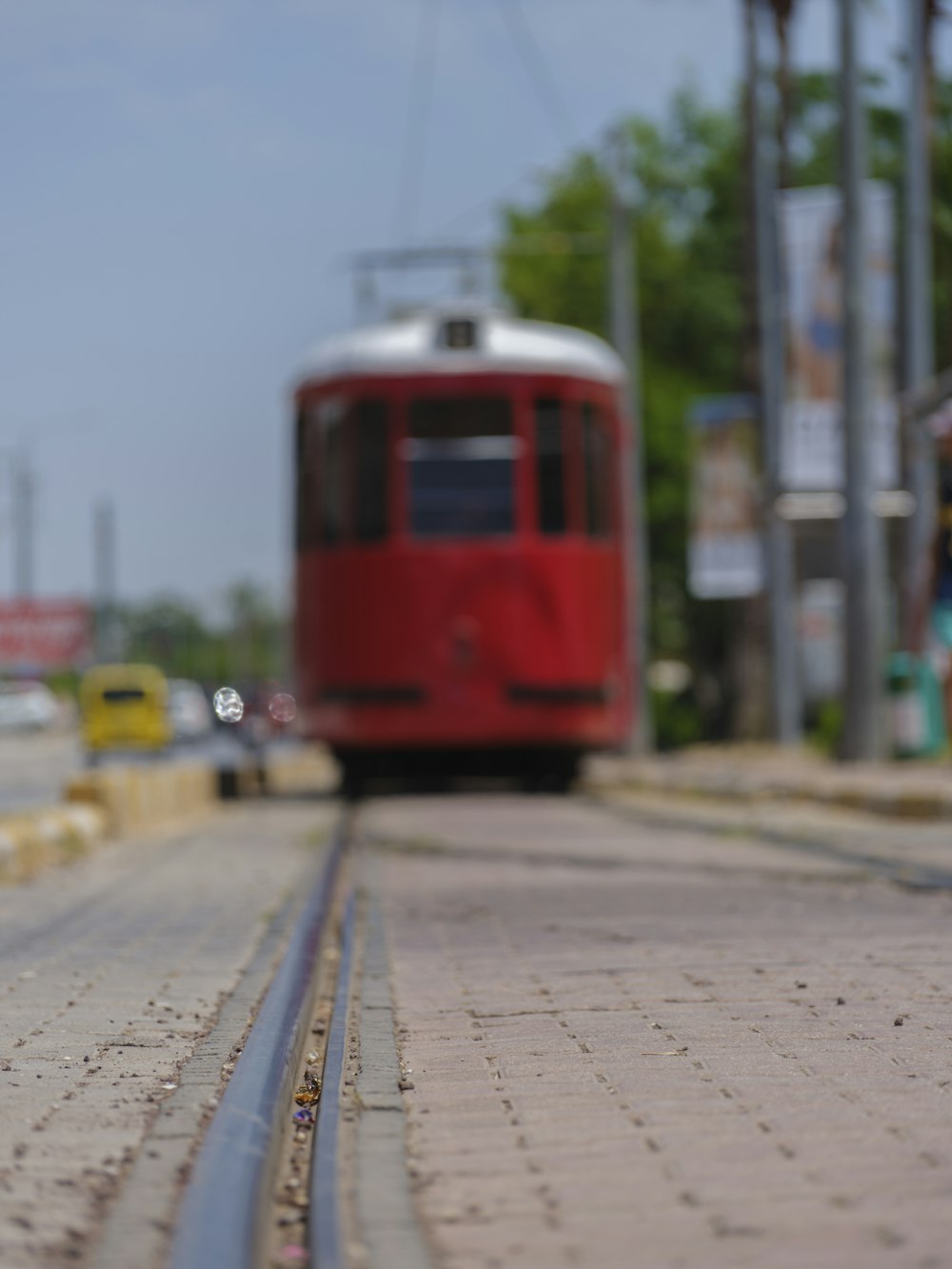 Ein roter Zug, der neben einer Straße die Bahngleise hinunterfährt
