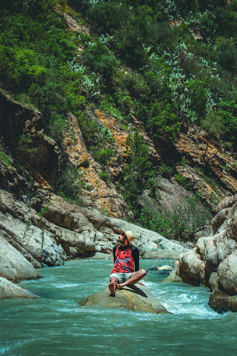 a man sitting on a rock in the middle of a river