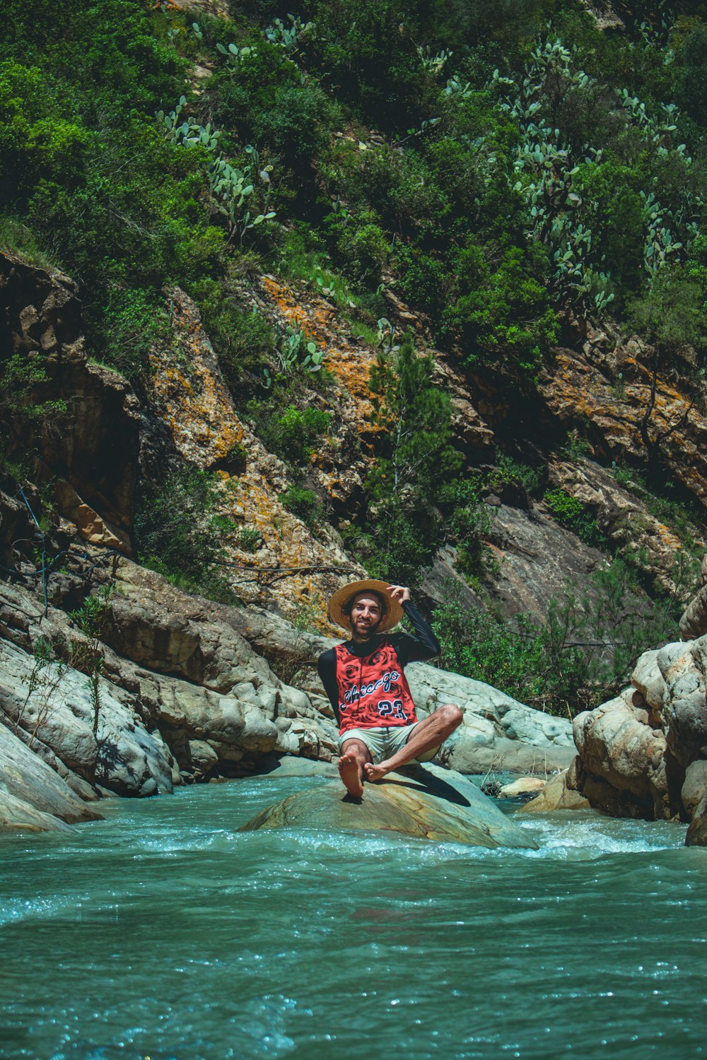 a man sitting on a rock in the middle of a river