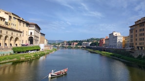 A tranquil river scene with small boats near historic structures.