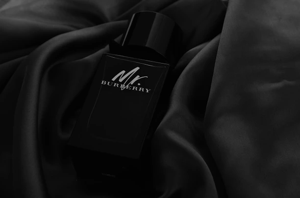 A sleek, modern perfume bottle with masculine design elements on a dark textured background.