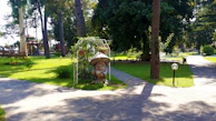 A peaceful garden scene featuring a ceramic gnome statue beside a blooming flower bed under soft sunlight.