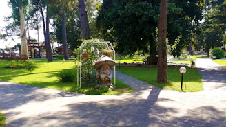 A peaceful garden scene featuring a ceramic gnome statue beside a blooming flower bed under soft sunlight.