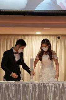 A cinematic wide shot of a couple in elegant attire, their faces partially obscured by artistic masks under moody lighting