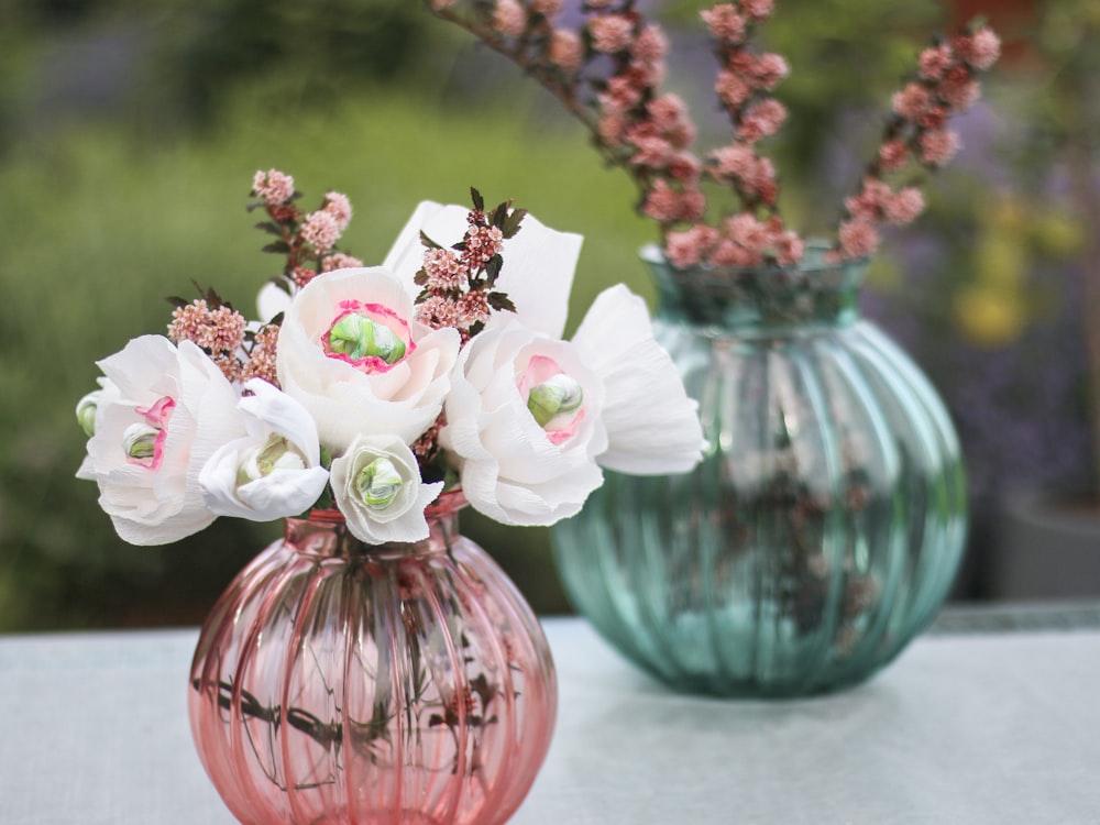 two vases with flowers in them sitting on a table